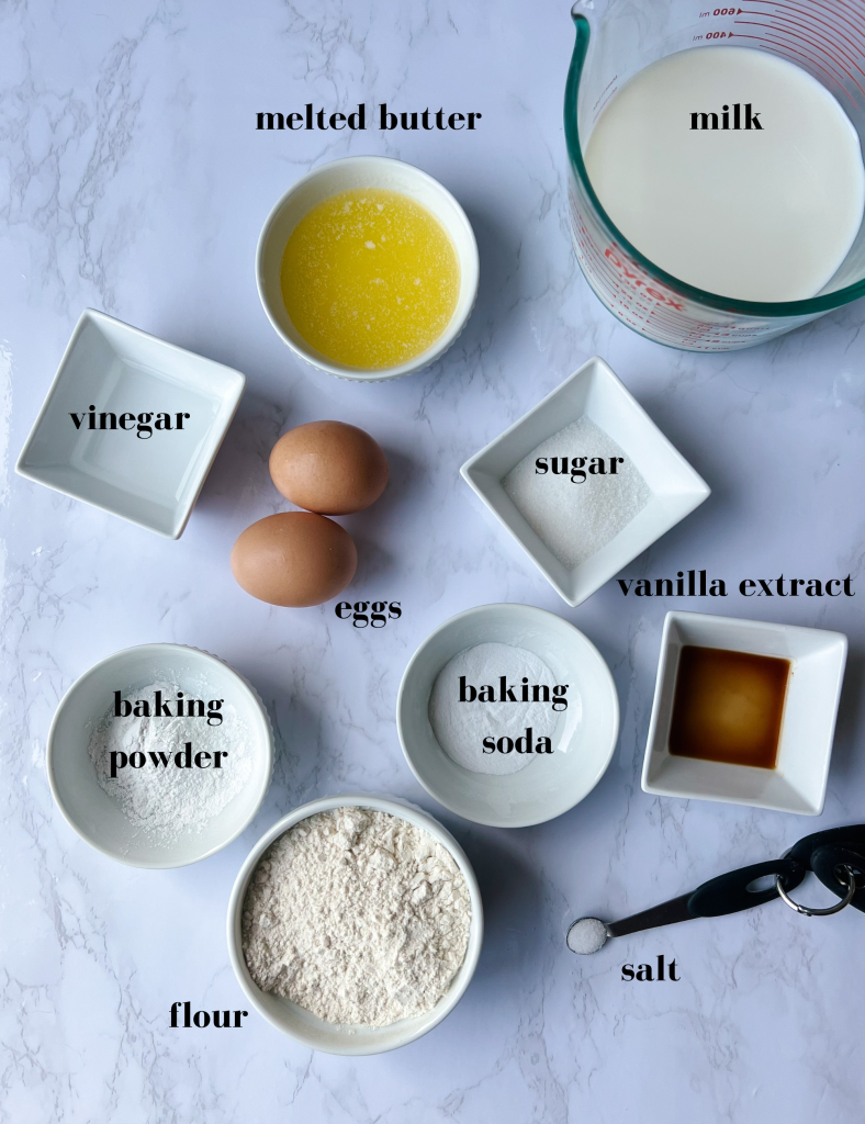 picture of ingredients for the pancakes: milk, vinegar, melted butter, granulated sugar, baking powder, baking soda, salt, vanilla extract, flour, eggs