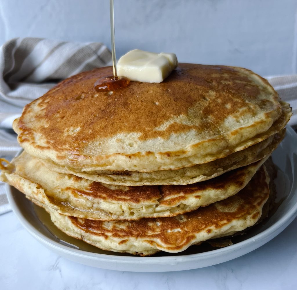 stack of buttermilk pancakes with syrup and a pad of butter on top