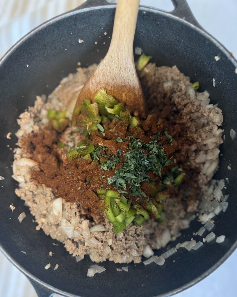 green pepper, chili powder, oregano added to cooked beef in pot