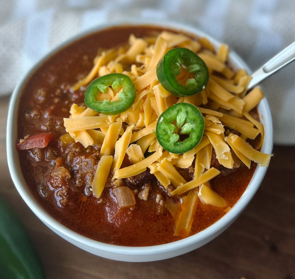 homemade chili topped with shredded cheese and jalapenos