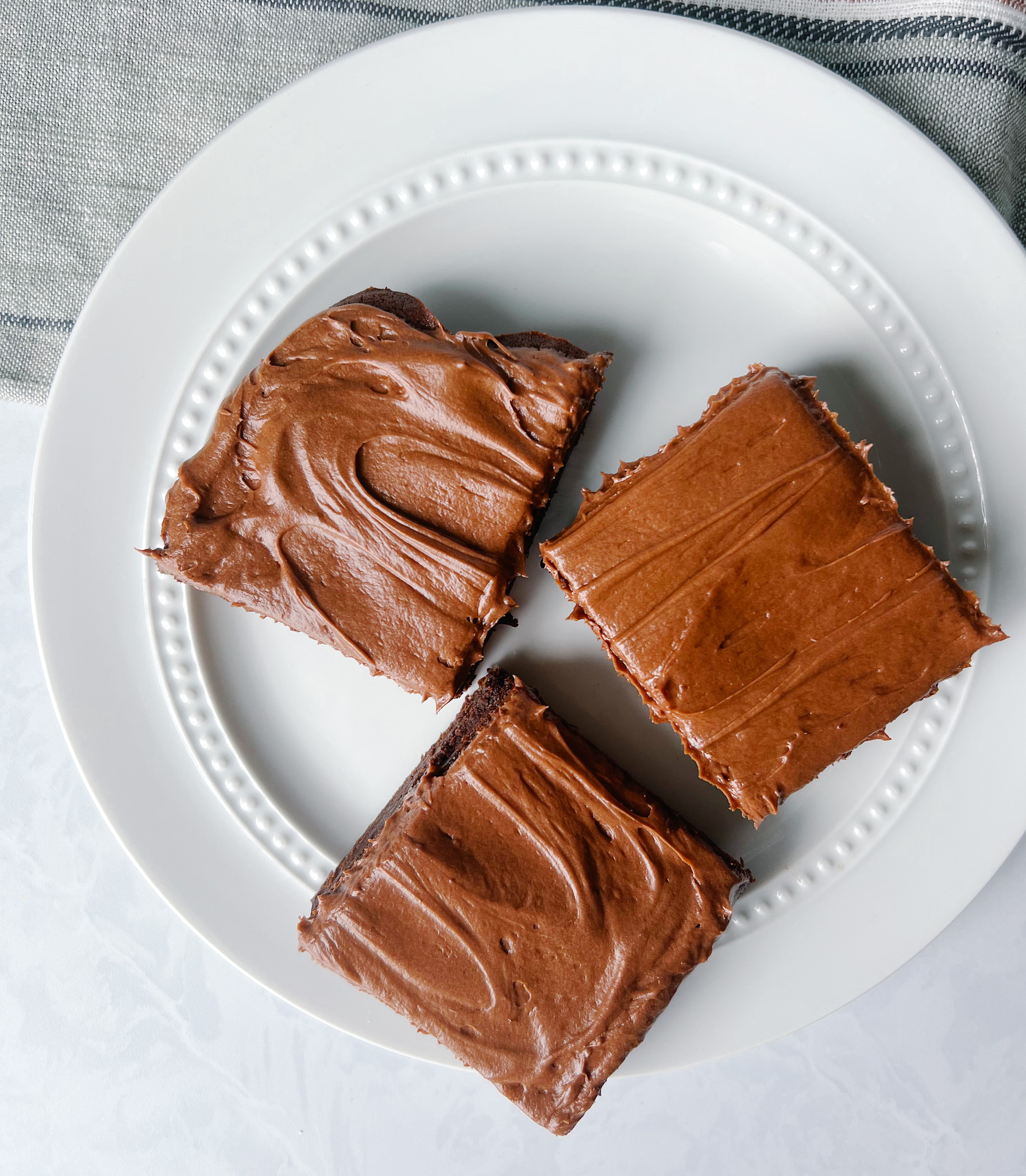 Plate of three frosted brownies.