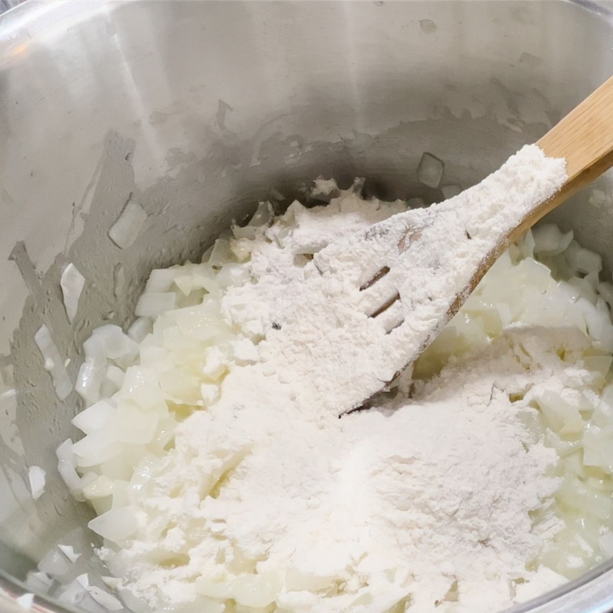 adding flour to a stockpot with butter and chopped onions.