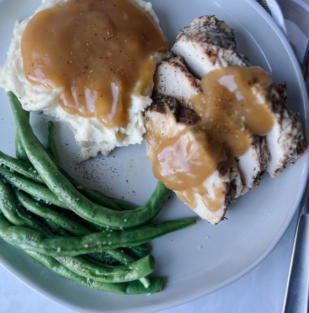 turkey dinner with gravy on top, mashed potatoes and gravy and green beans