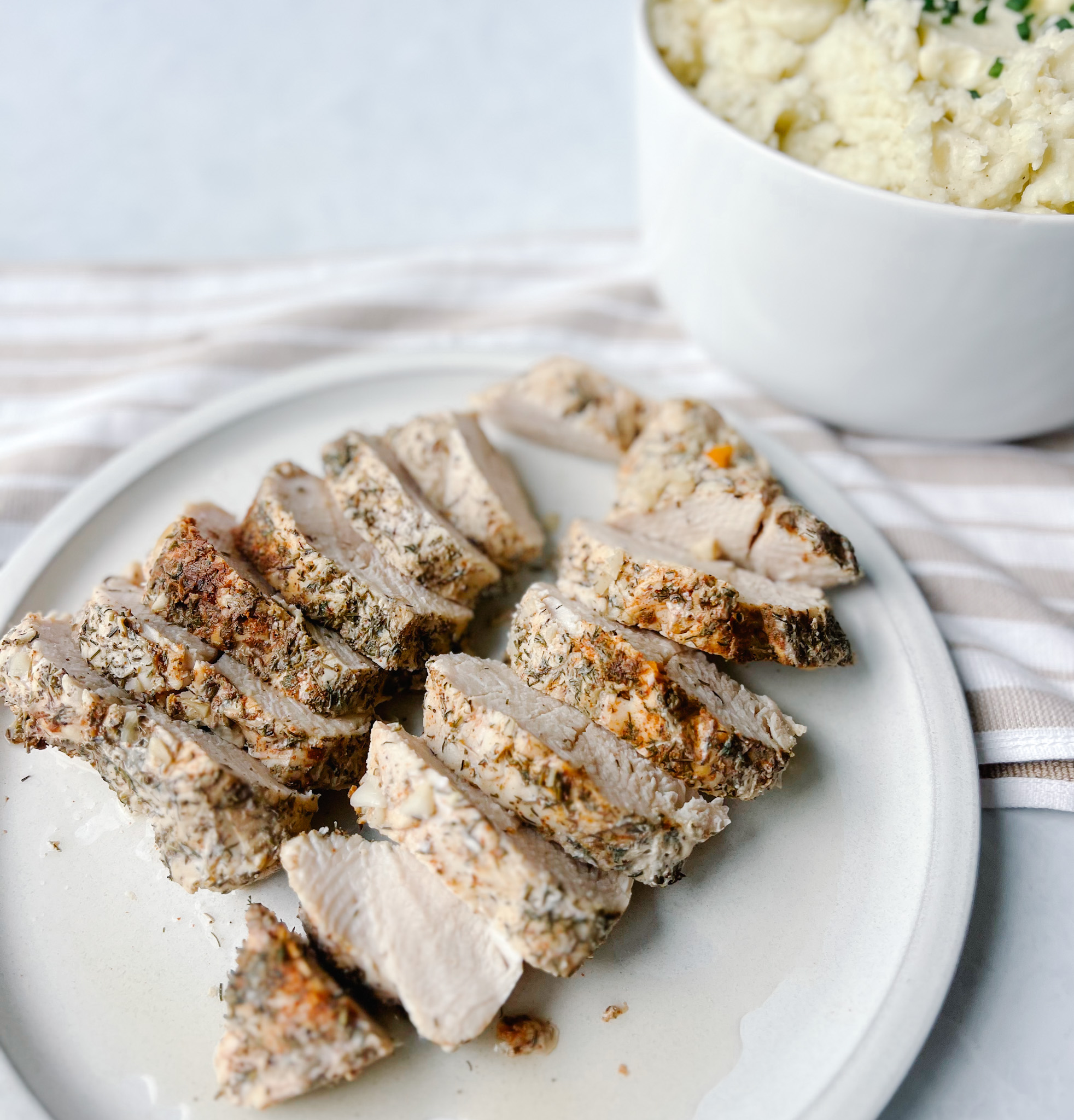 turkey tenderloin sliced with mashed potatoes in the background
