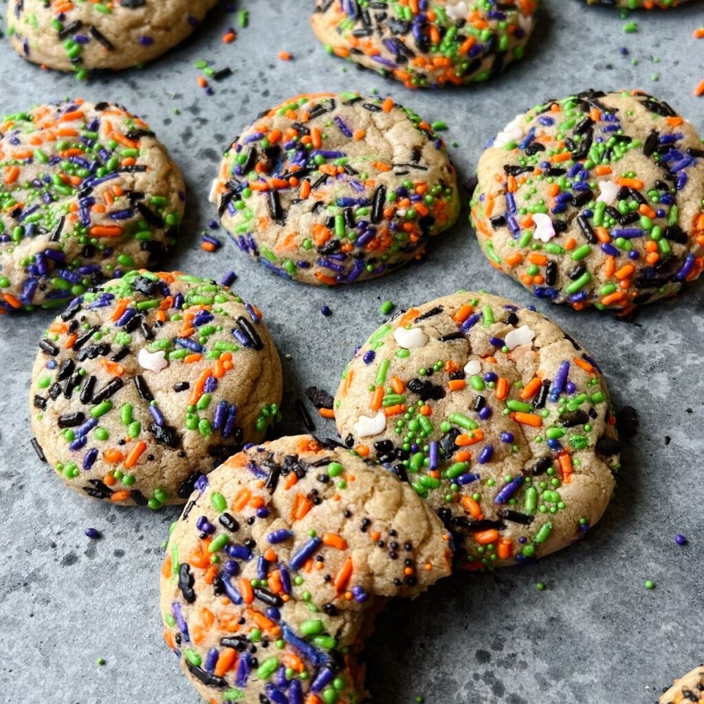 Sprinkled brown butter sugar cookies on a counter, with the first one taken a bite out of.