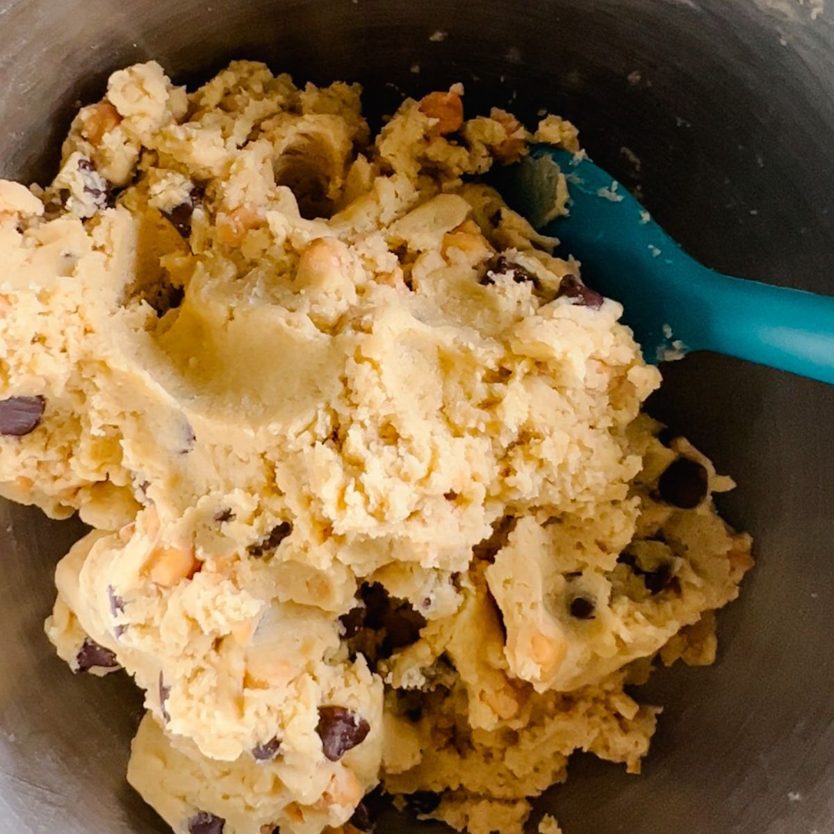 Caramel chocolate chip cookie dough in a mixing bowl mixed together.