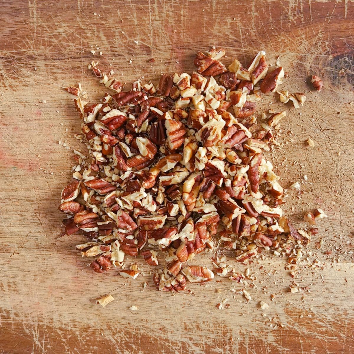 Chopped toasted pecans on a cutting board.