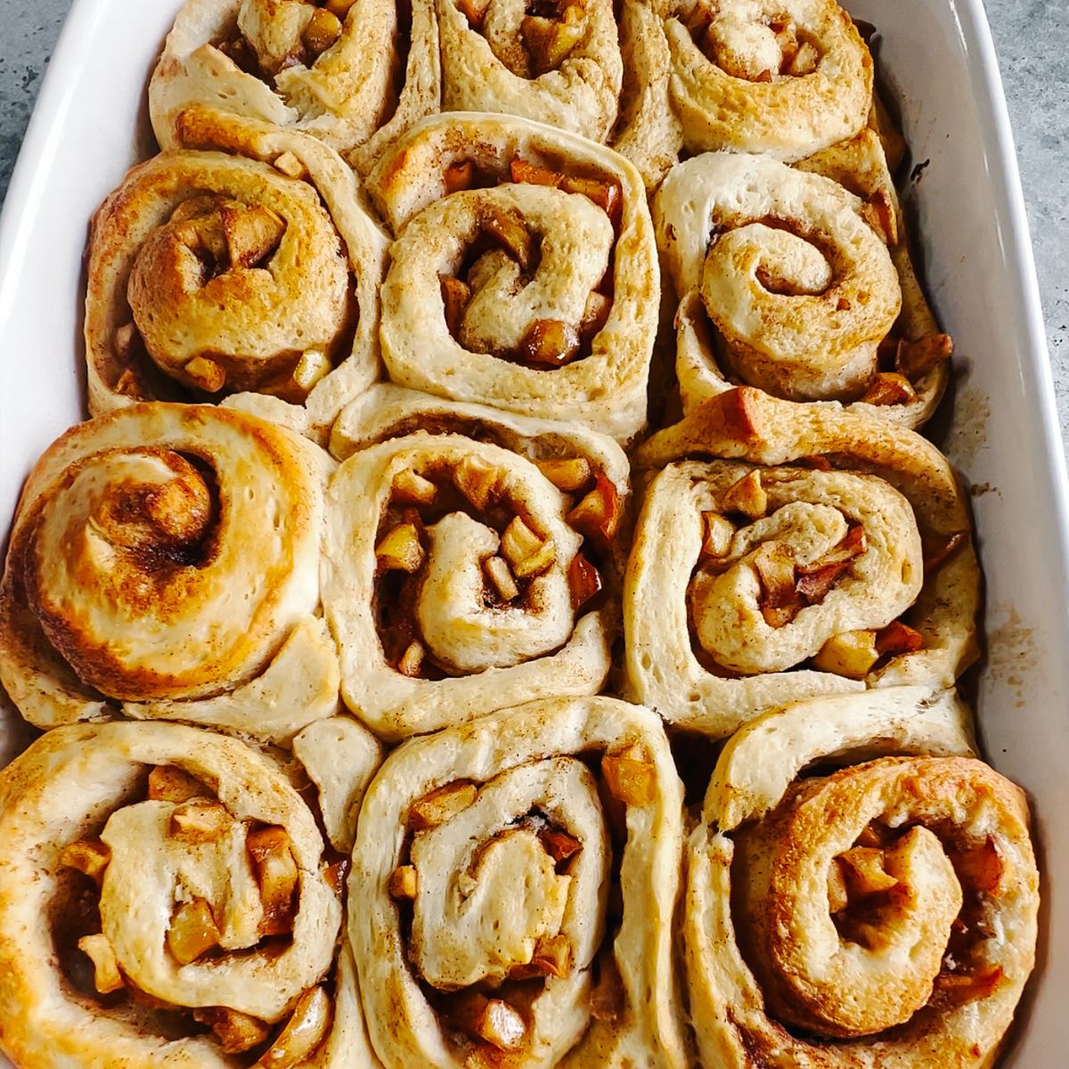 Twelve baked cinnamon rolls in a baking dish.