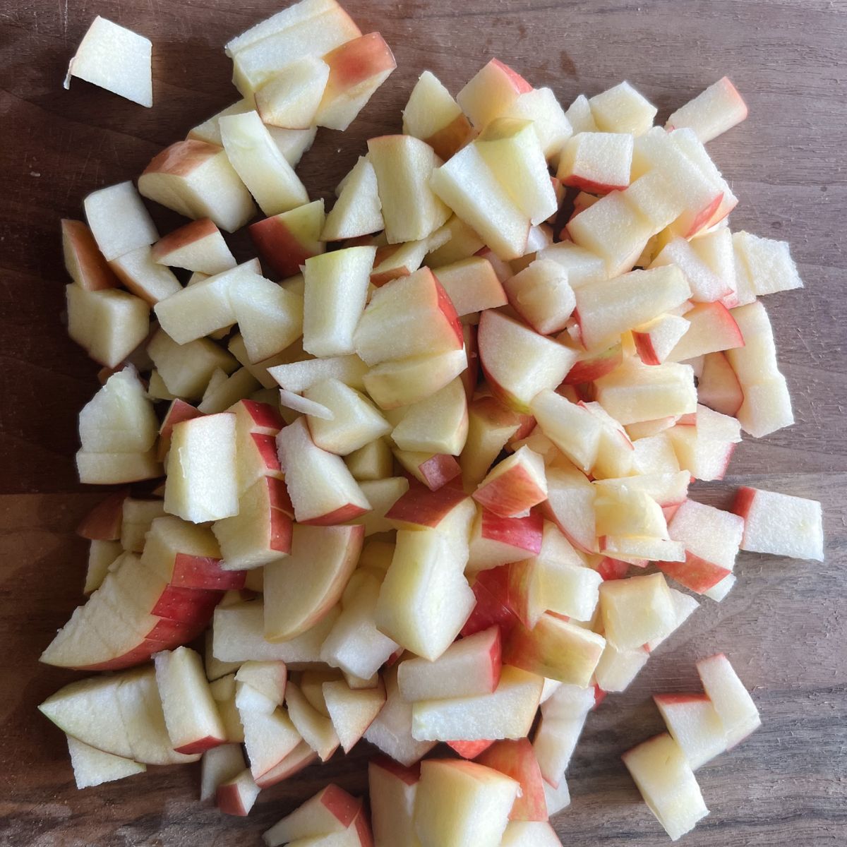 Three chopped apples on a wooden cutting board.