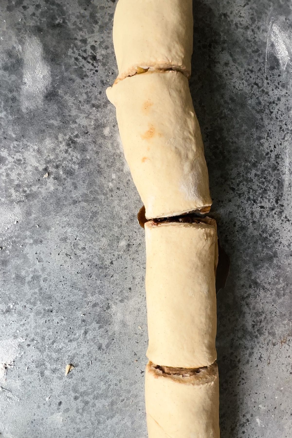 Cinnamon roll dough rolled into a cylinder and cut in fourths.