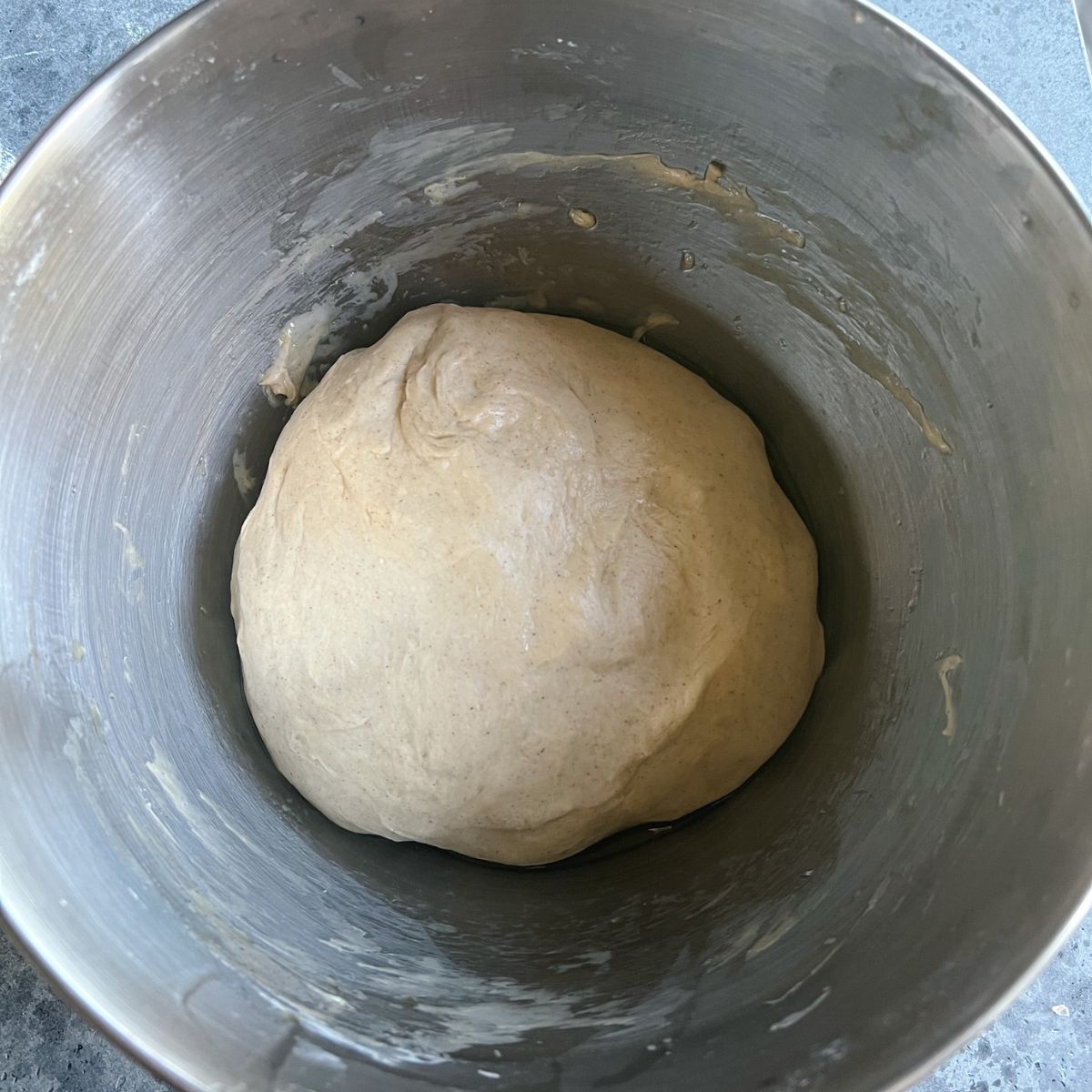 A ball of cinnamon roll dough in a mixing bowl.