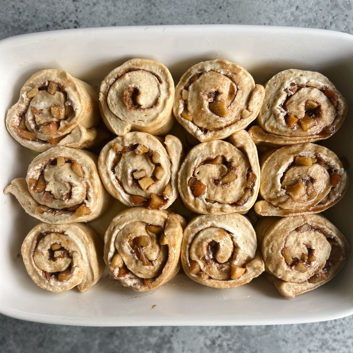 Twelve unbaked cinnamon rolls in a 9x13 baking dish. 
