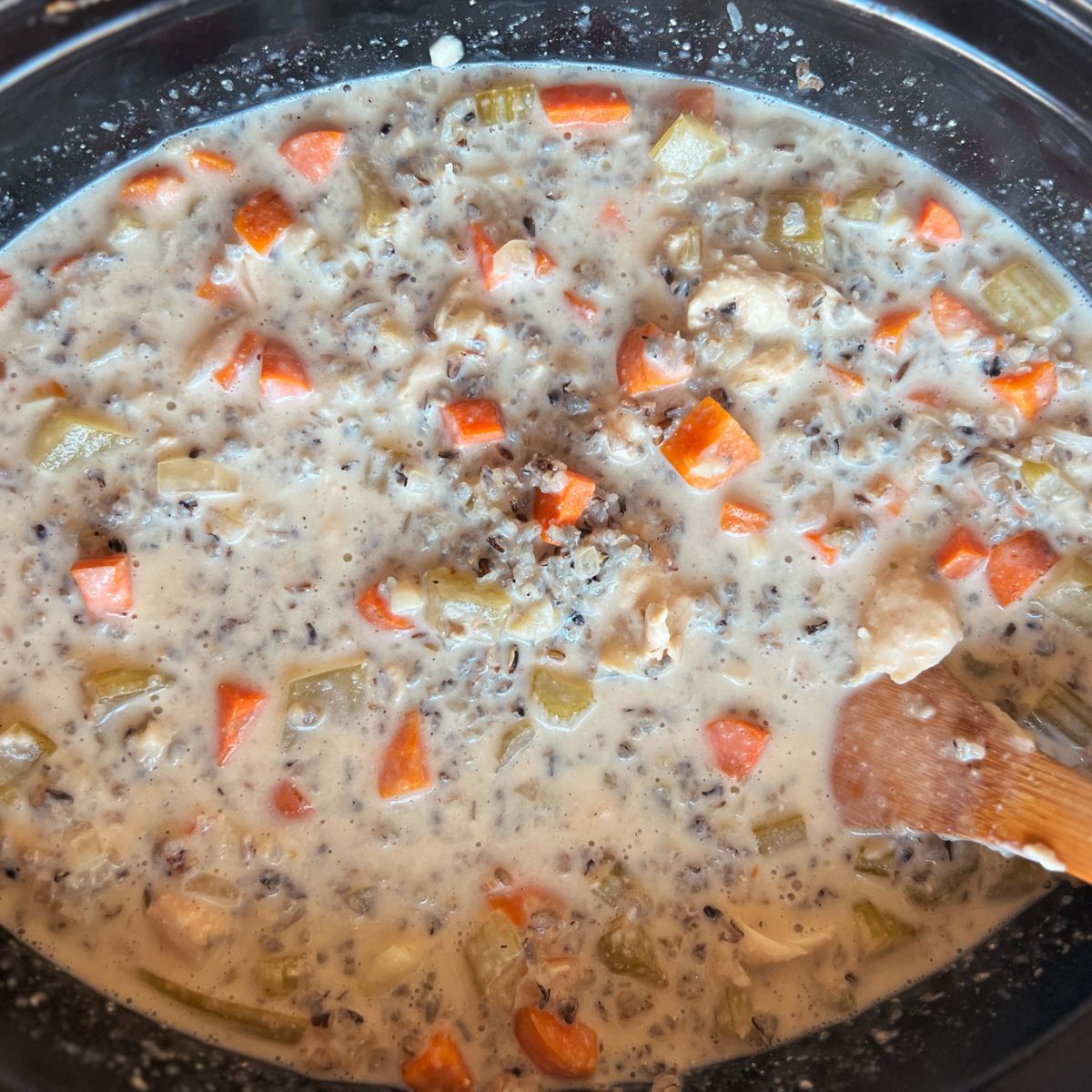 Crockpot with fully cooked chicken wild rice and all ingredients mixed together in it.