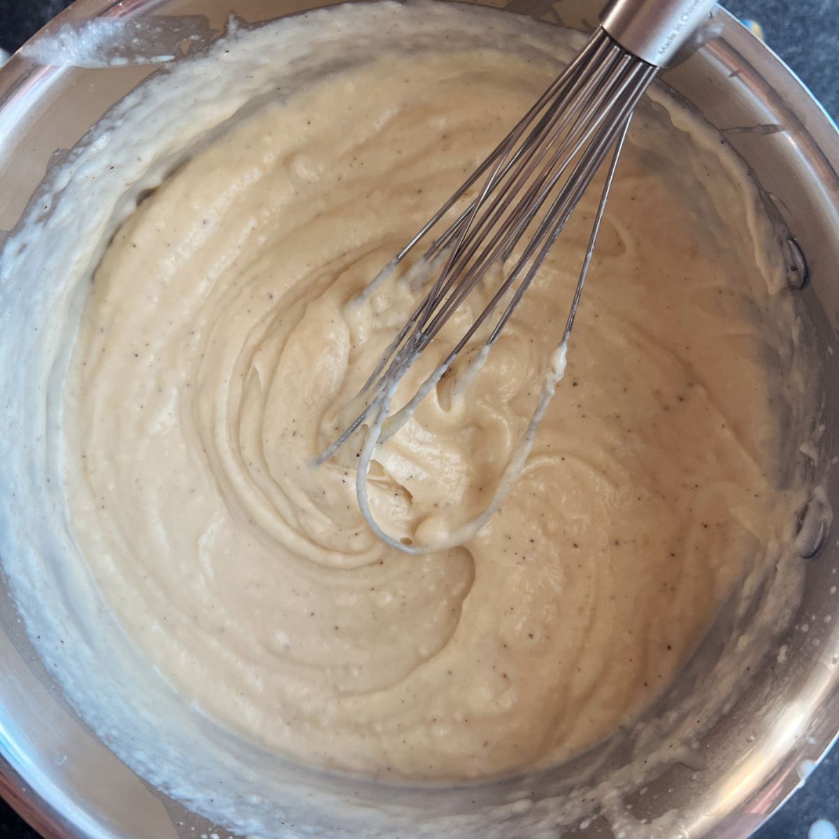 Saucepan with flour mixture and heavy cream added to show a creamy paste.