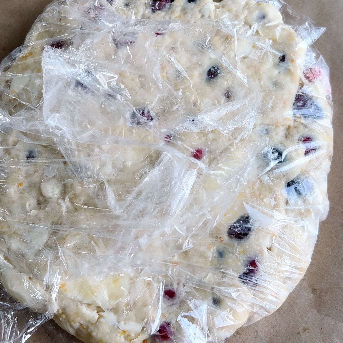 Disc of dough wrapped in plastic wrap.