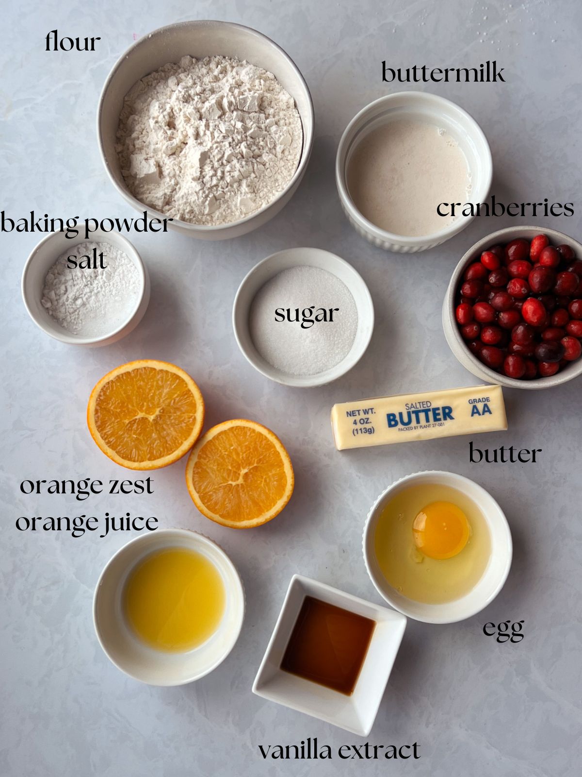 Ingredients for the orange cranberry scones: flour, buttermilk, cranberries, baking powder, salt, sugar, butter, orange zest, orange juice, egg, vanilla extract. 