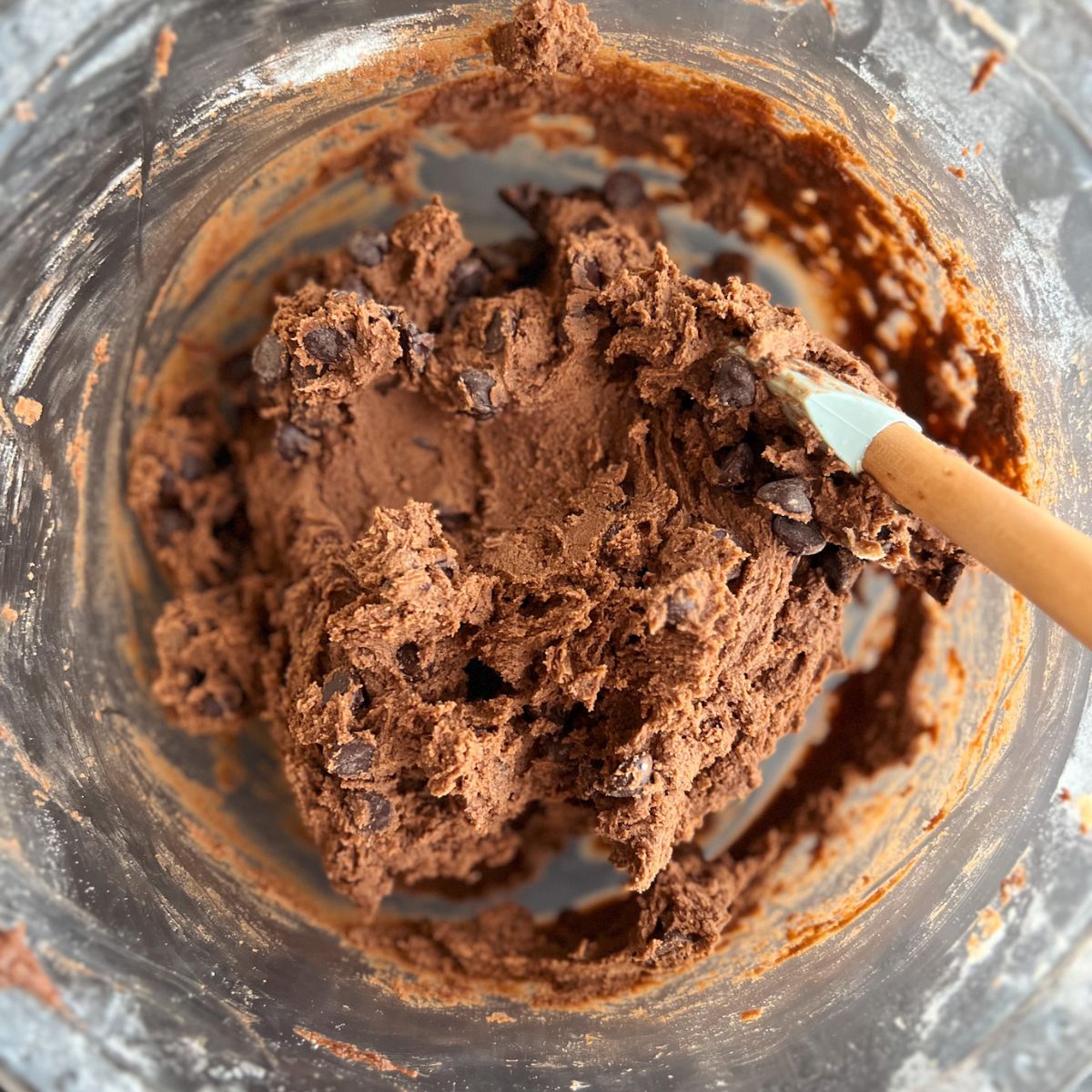 Cookie dough with chocolate chips added in a mixing bowl. 
