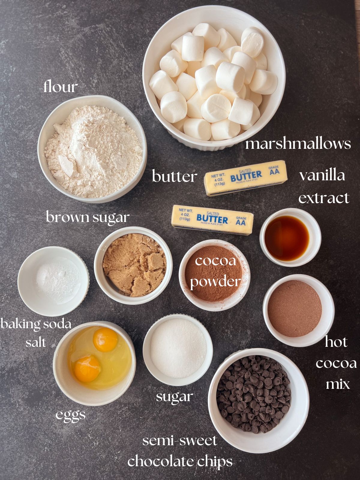 Ingredient shot for the hot cocoa cookies: marshmallows, flour, butter, vanilla extract, brown sugar, granulated sugar, hot cocoa mix, cocoa powder, baking soda, salt, semi-sweet chocolate chips, eggs.