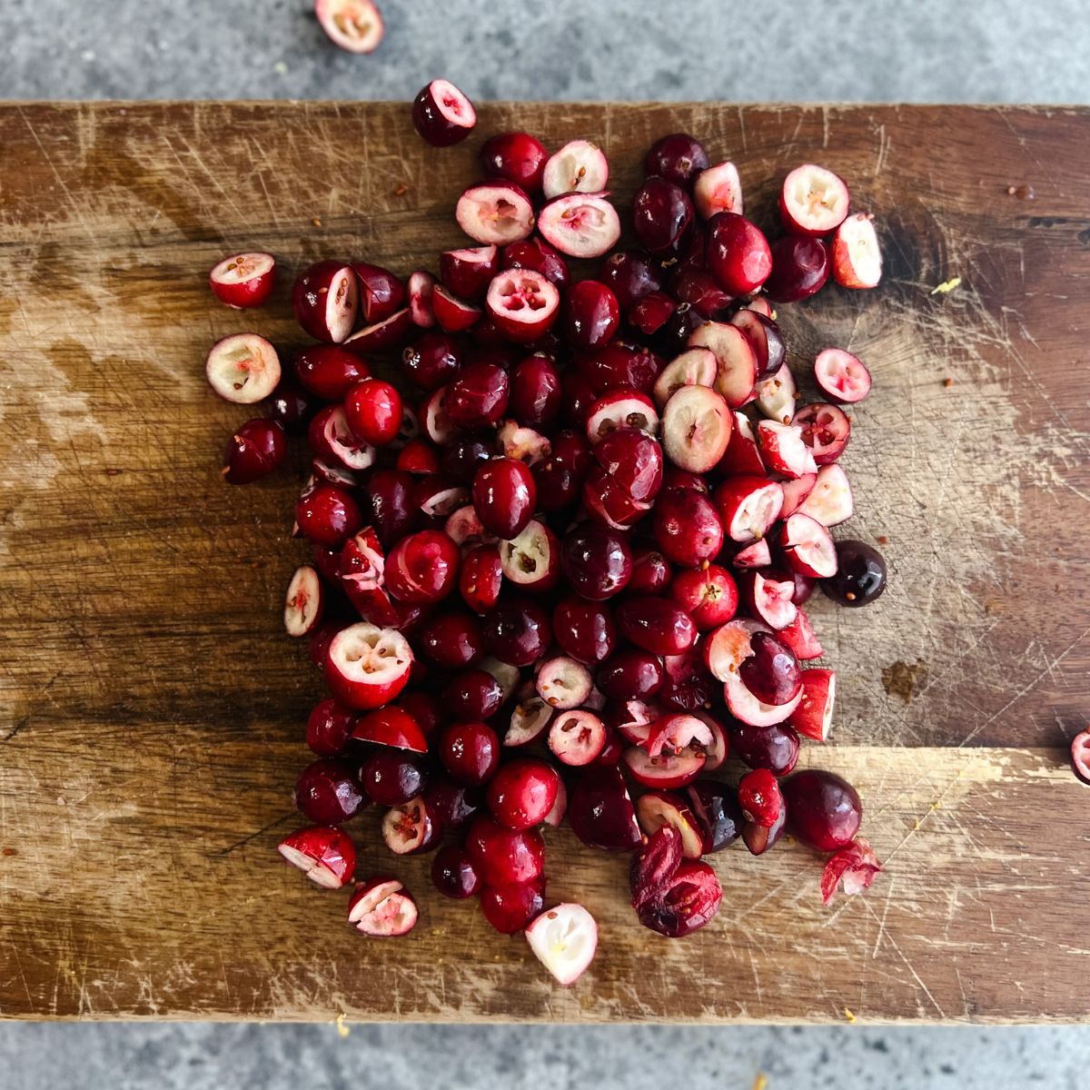 Chopped cranberries on a wooden cutting board.