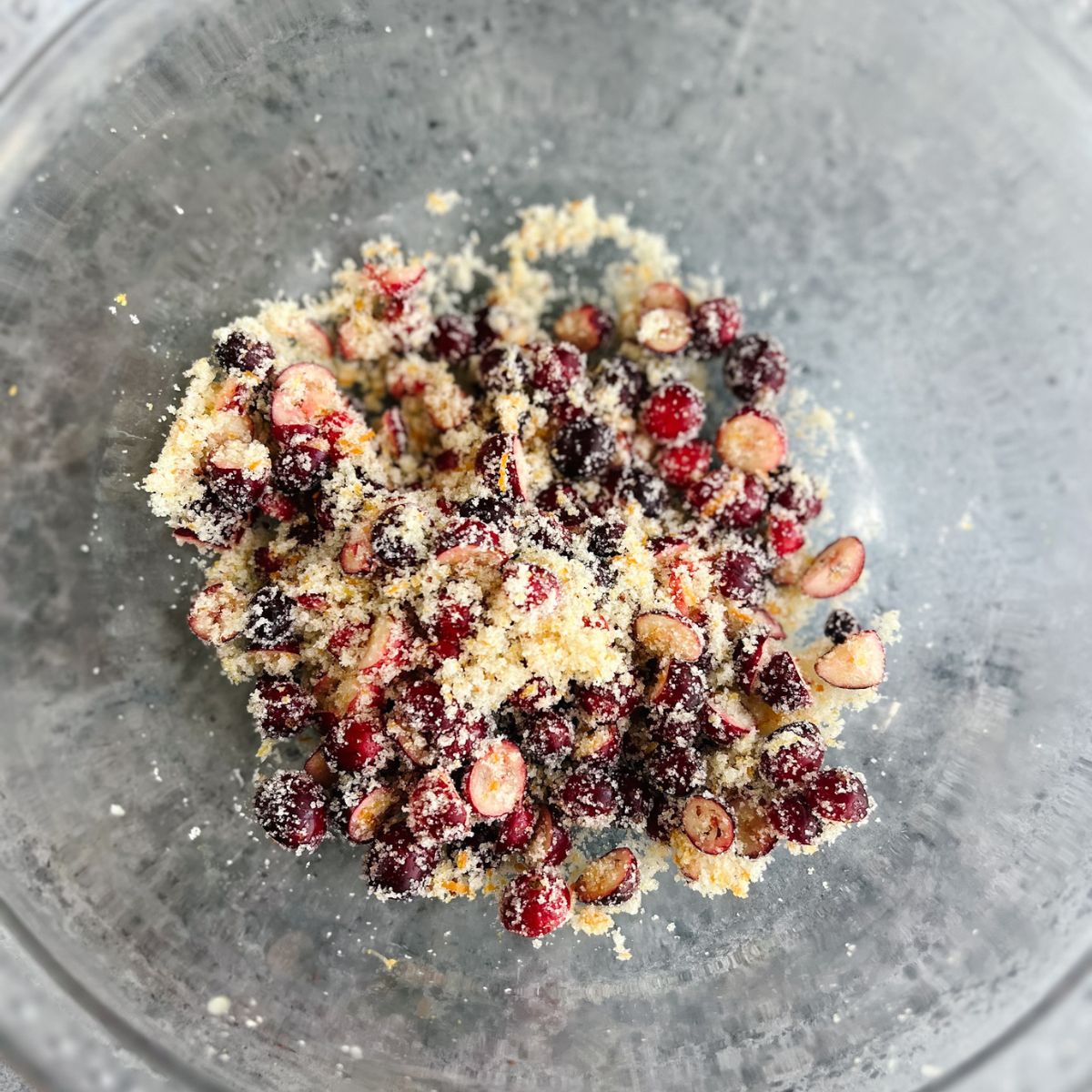 Sugar mixed with cranberries and orange zest in a mixing bowl. 