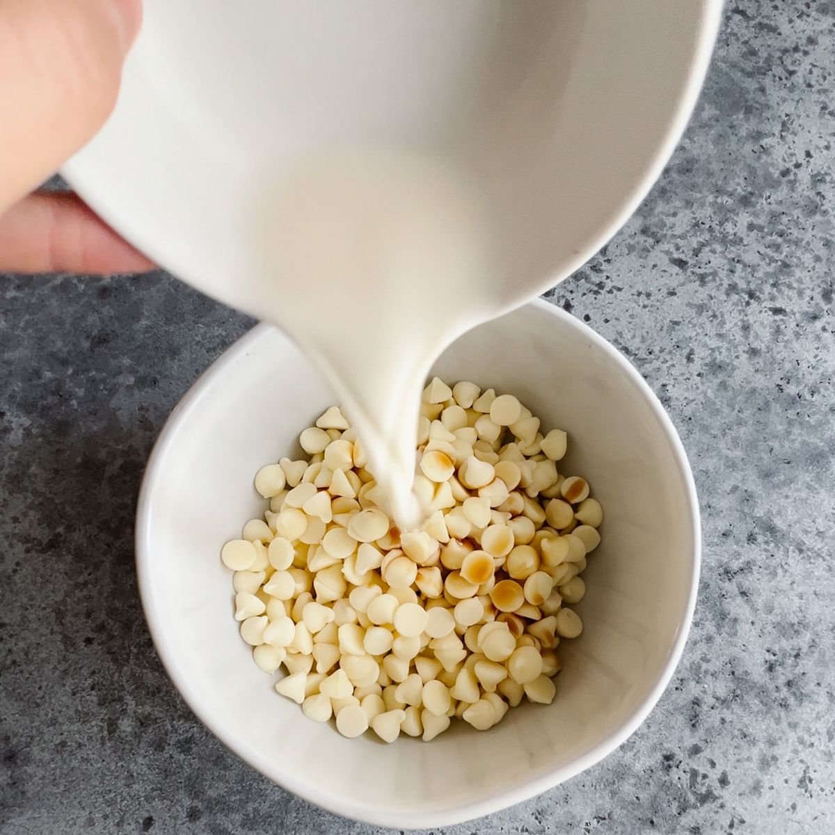 Pouring milk into a bowl of white chocolate chips.