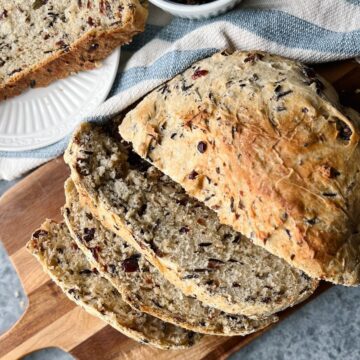 Cranberry wild rice bread sliced on a wooden cutting board