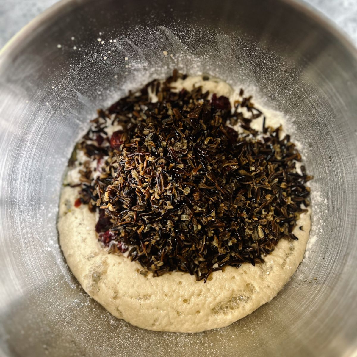 Mixing bowl with wild rice, cranberries, flour, olive oil, honey, yeast, water, and salt. 