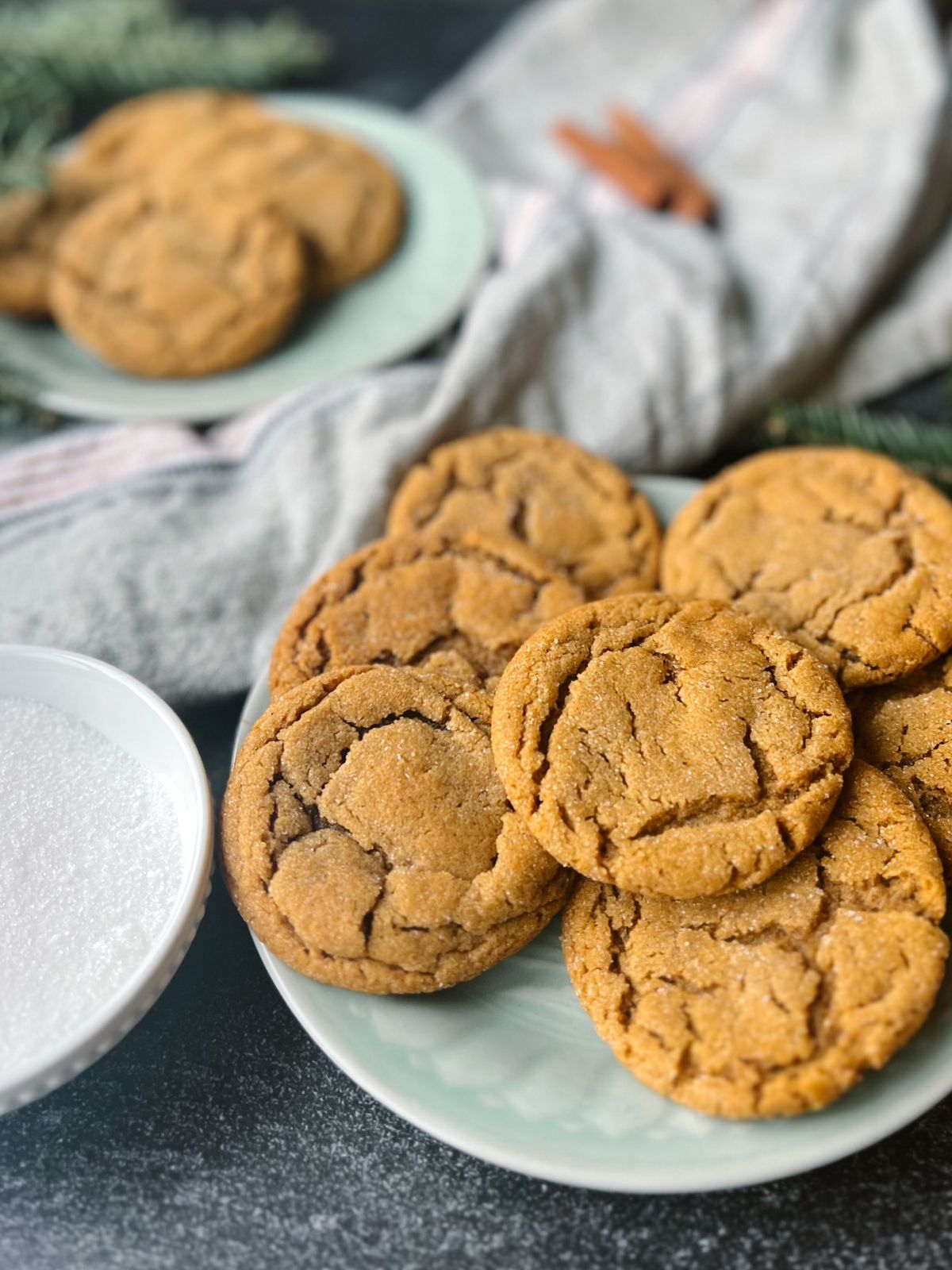Close up picture of ginger snap cookies on a plate with a plate of cookies behind them. 