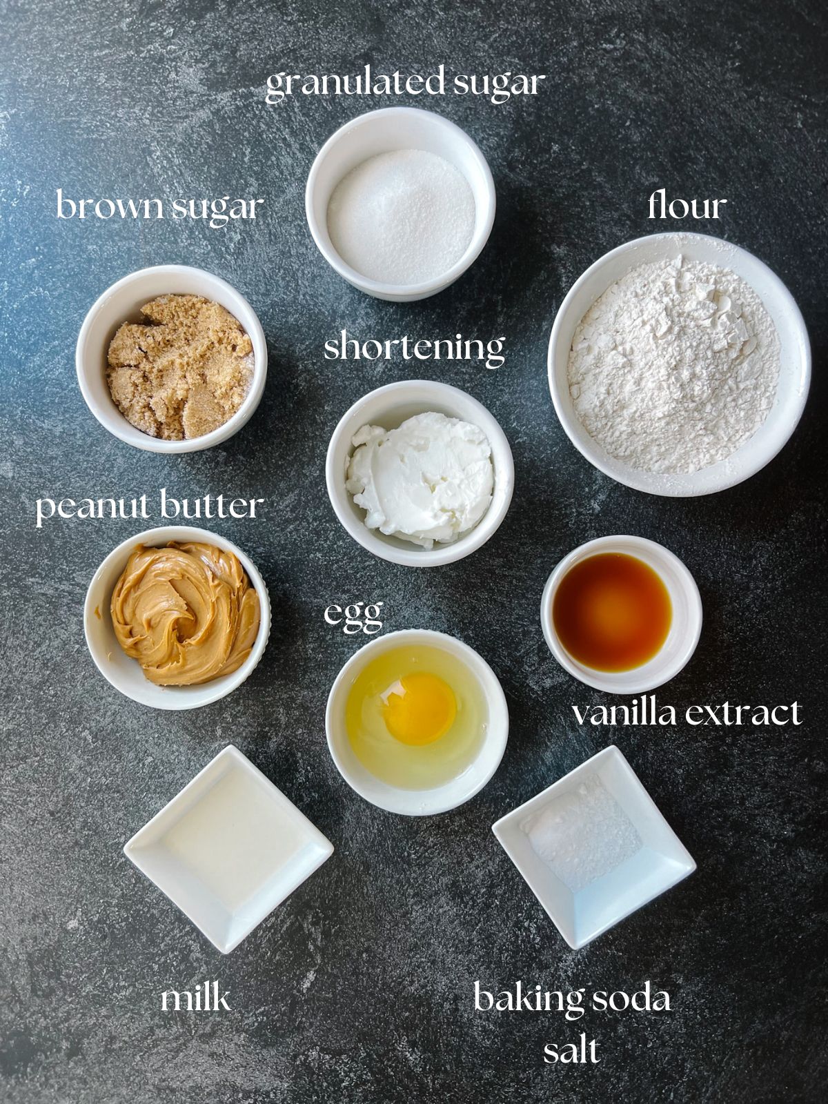 Ingredients for peanut butter blossoms: granulated sugar, brown sugar, flour, shortening, peanut butter, egg, vanilla extract, milk, baking soda, salt.