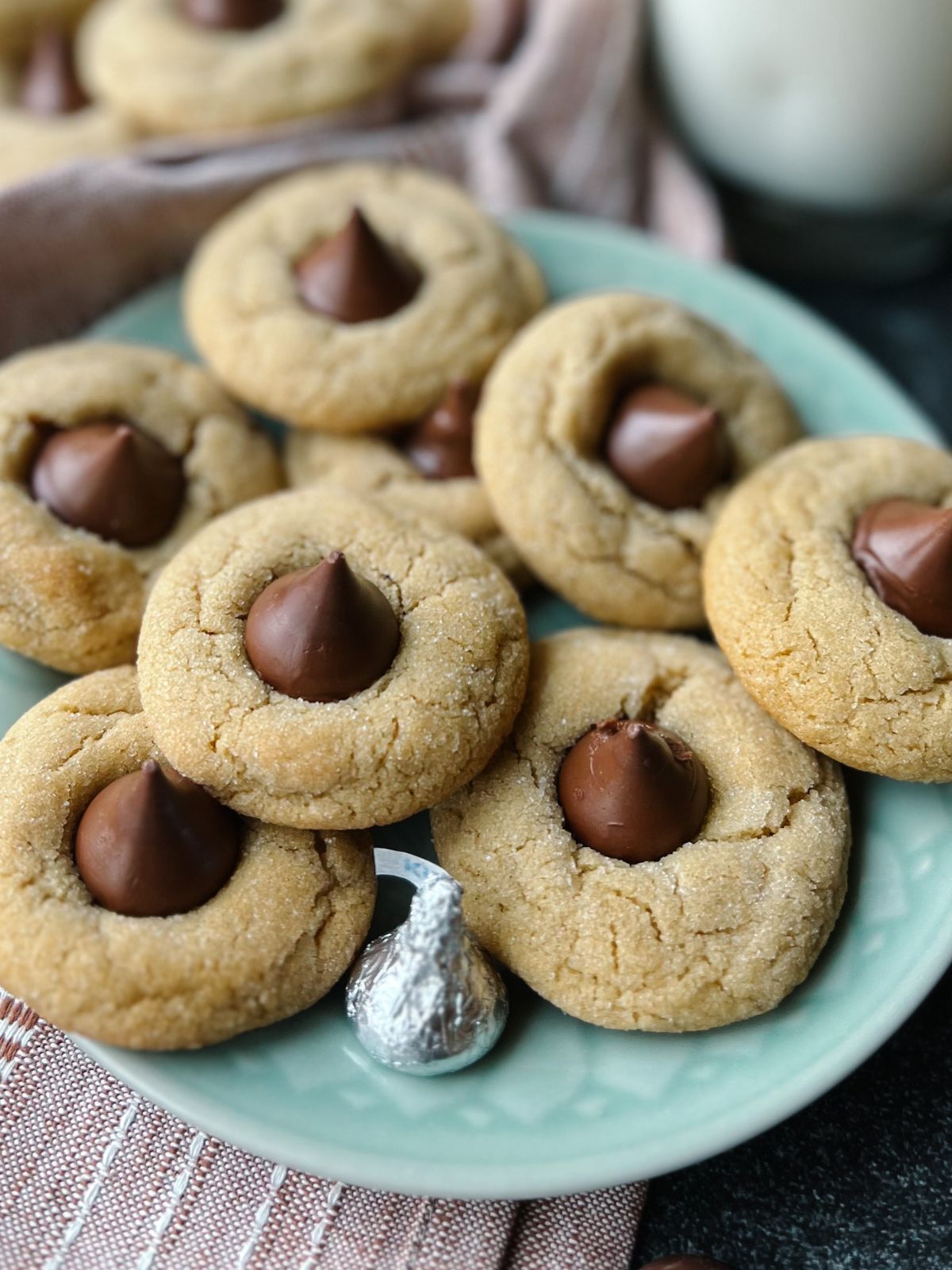 Plate of peanut butter blossoms with another plate of the cookies in the background.