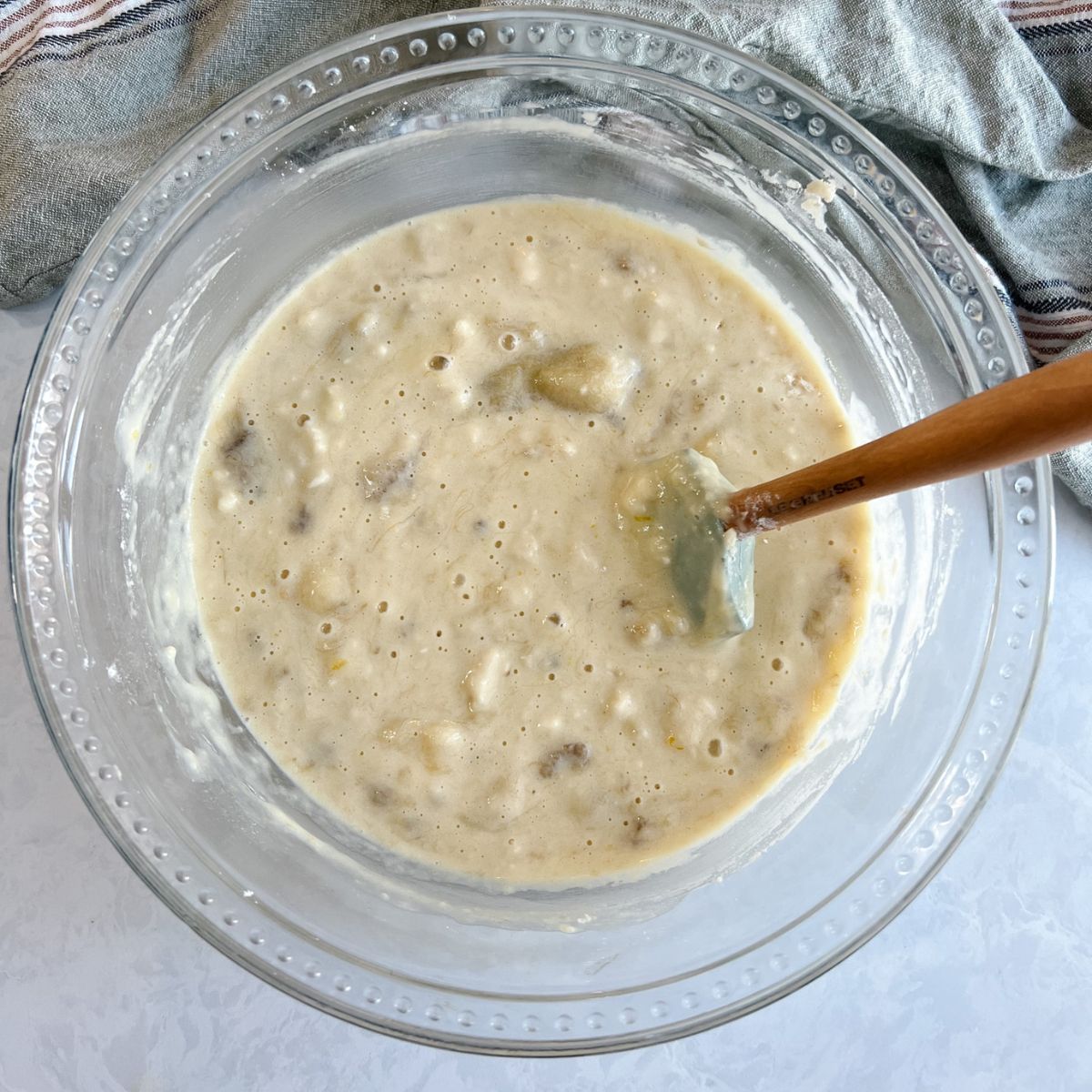 Banana bread batter in a mixing bowl with the cry ingredients and wet ingredients added together. 