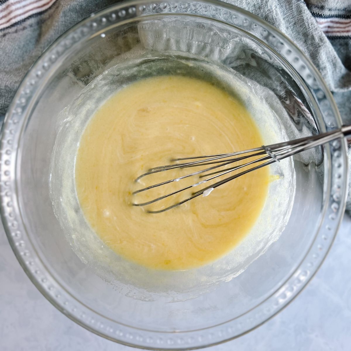 Mixing bowl with eggs, vanilla extract, sour cream, milk, and melted butter.
