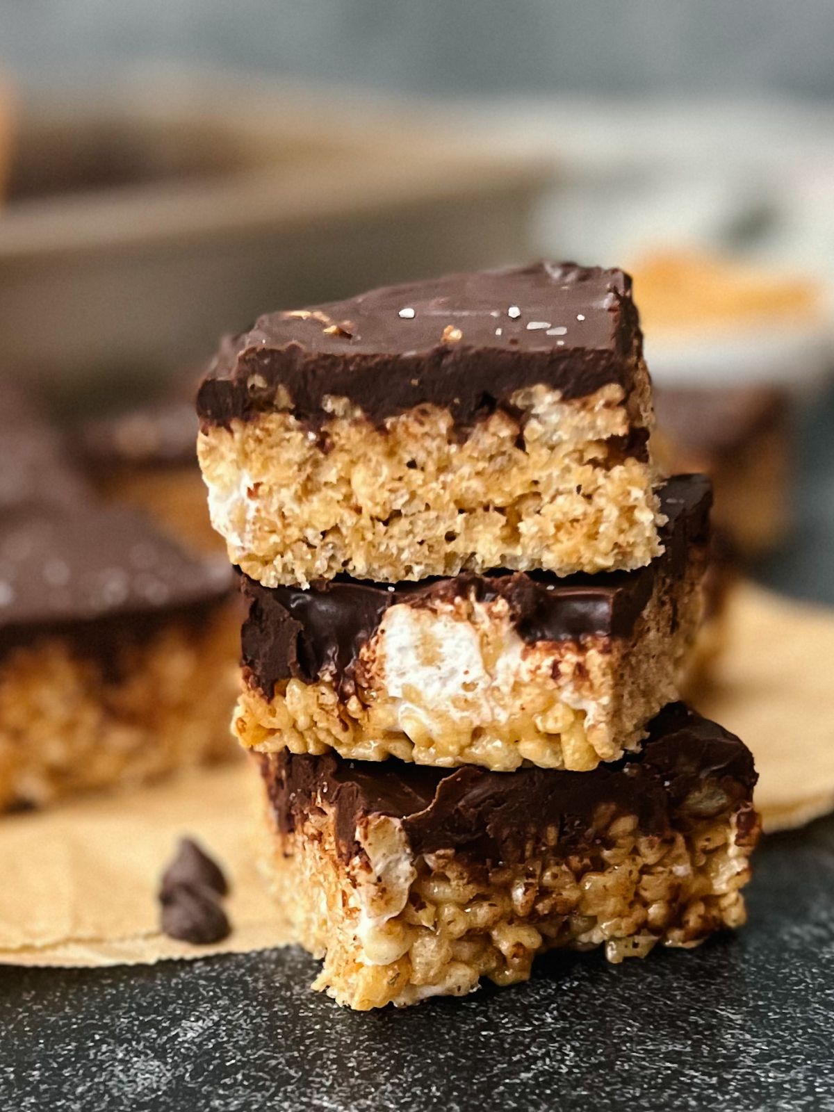 3 chocolate peanut butter krispie treats stacked on a counter.