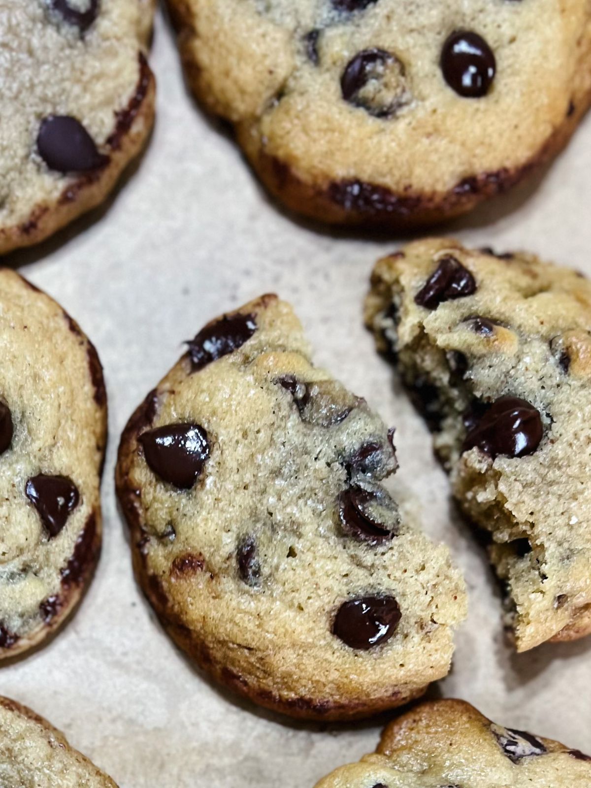 Freshly baked sourdough chocolate chip cookies on parchment paper.