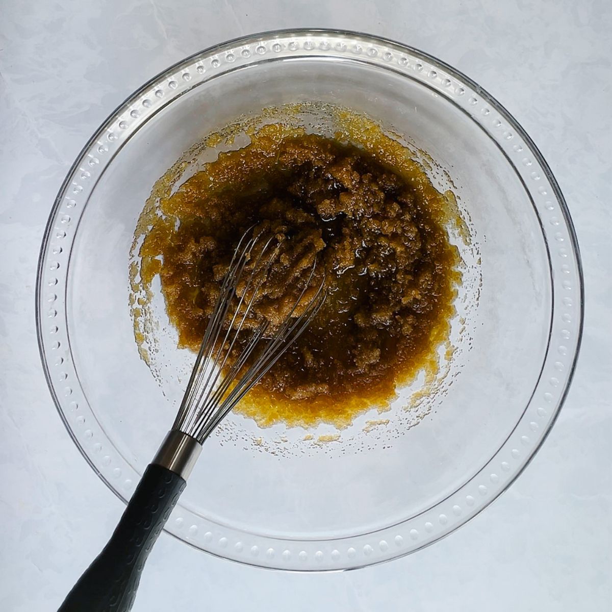Olive oil and brown sugar in a mixing bowl with whisk.