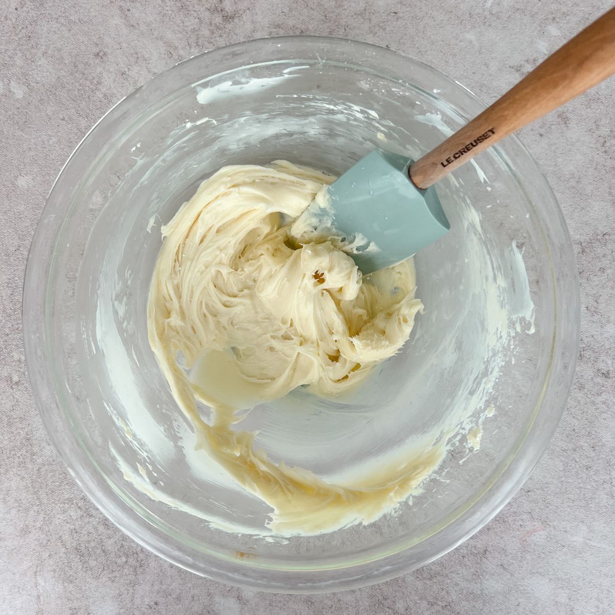 Cream cheese filling in a mixing bowl with a rubber spatula in the bowl.