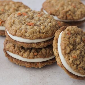 Carrot cake cookie sandwiches stacked on each other.