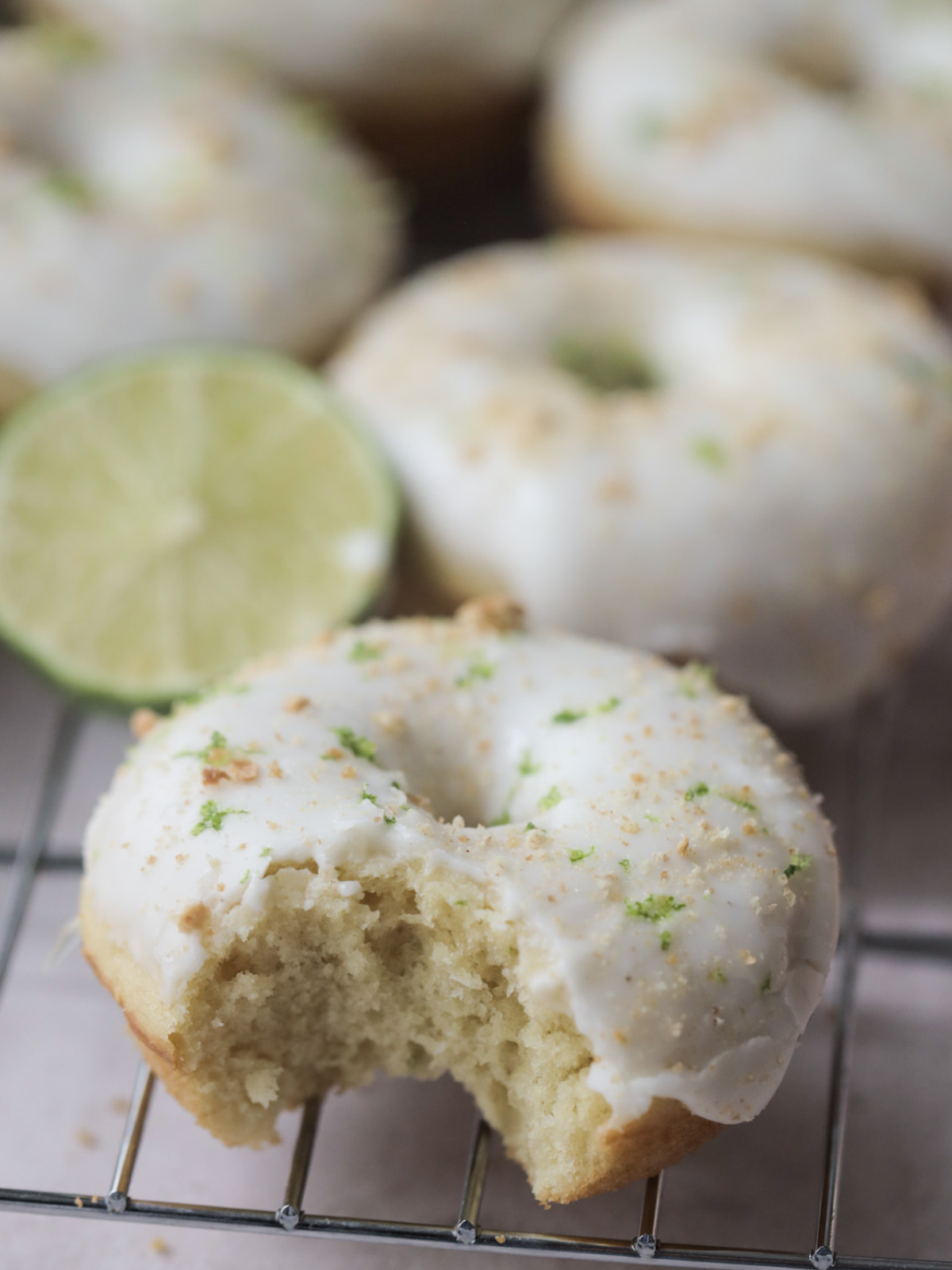Key lime sourdough doughnut with a bite taken out of it. It sits on a wire rack. 