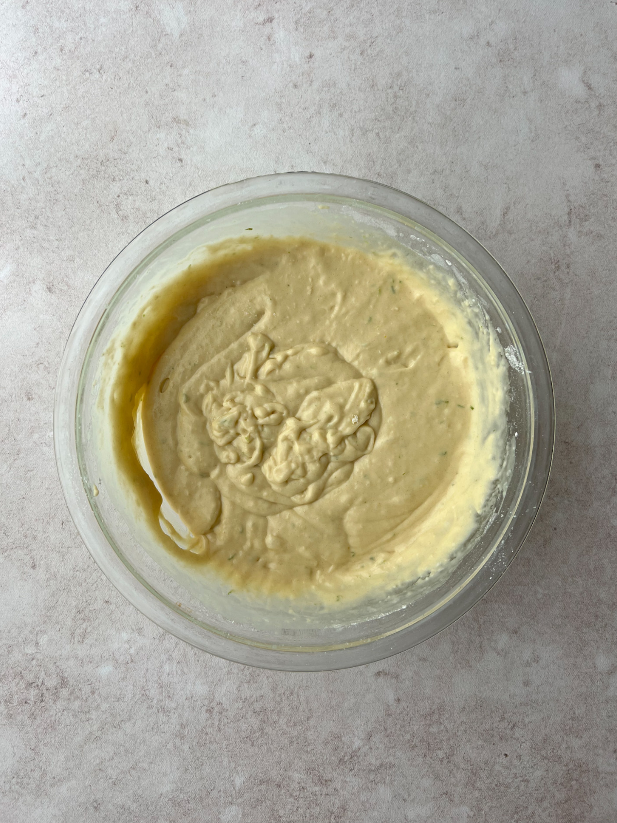 A glass mixing bowl with all the batter for the sourdough key lime donuts.