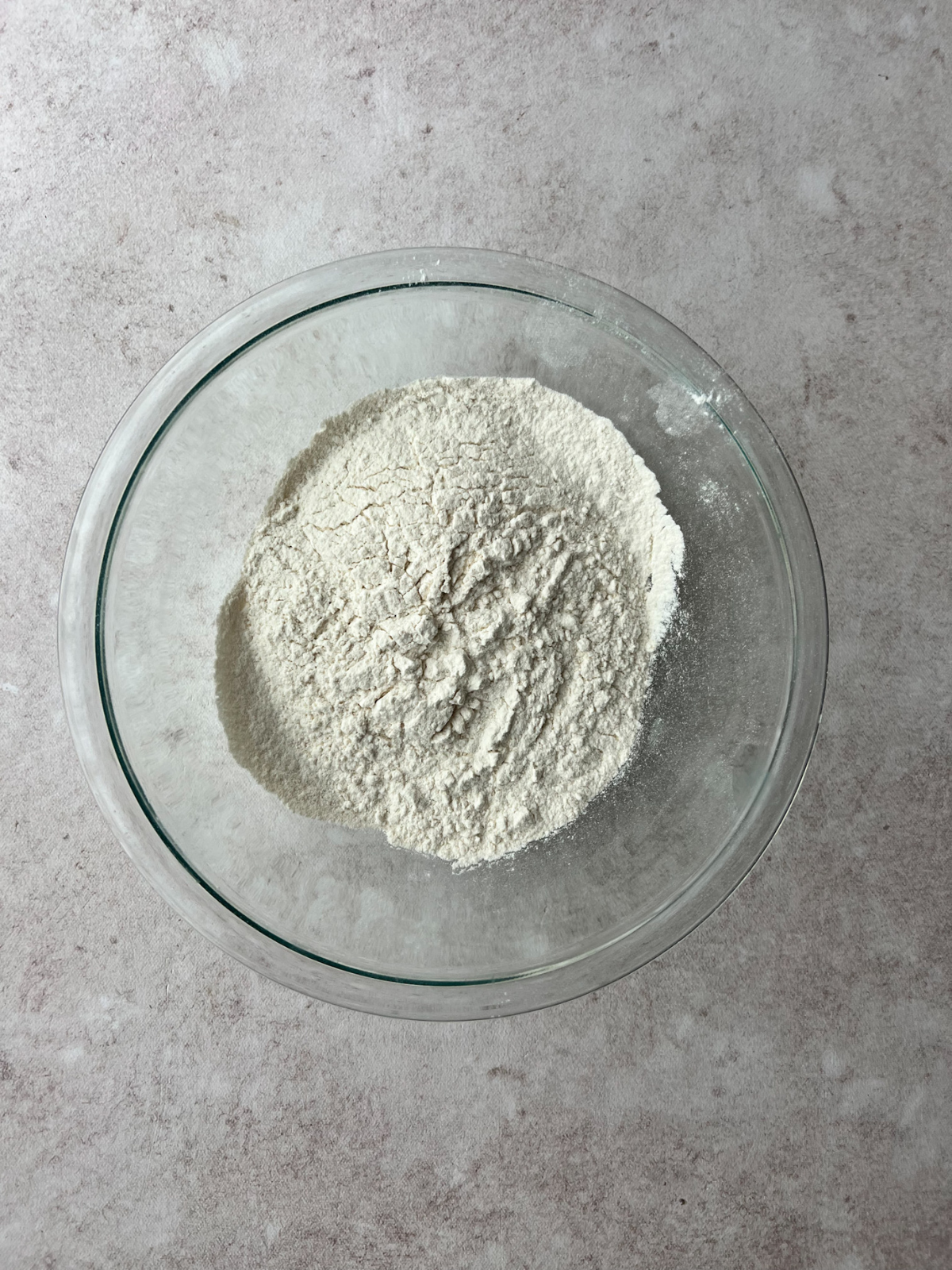 A glass mixing bowl with the dry ingredients for the key lime sourdough donuts in it.