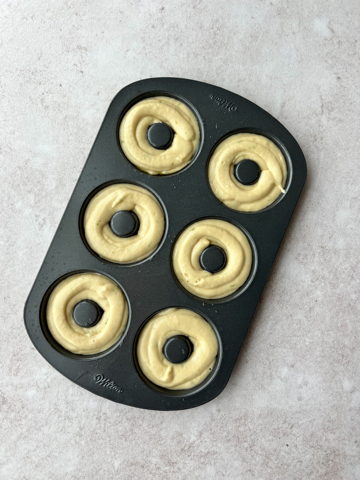 A donut pan with the batter of the sourdough key lime doughnuts.