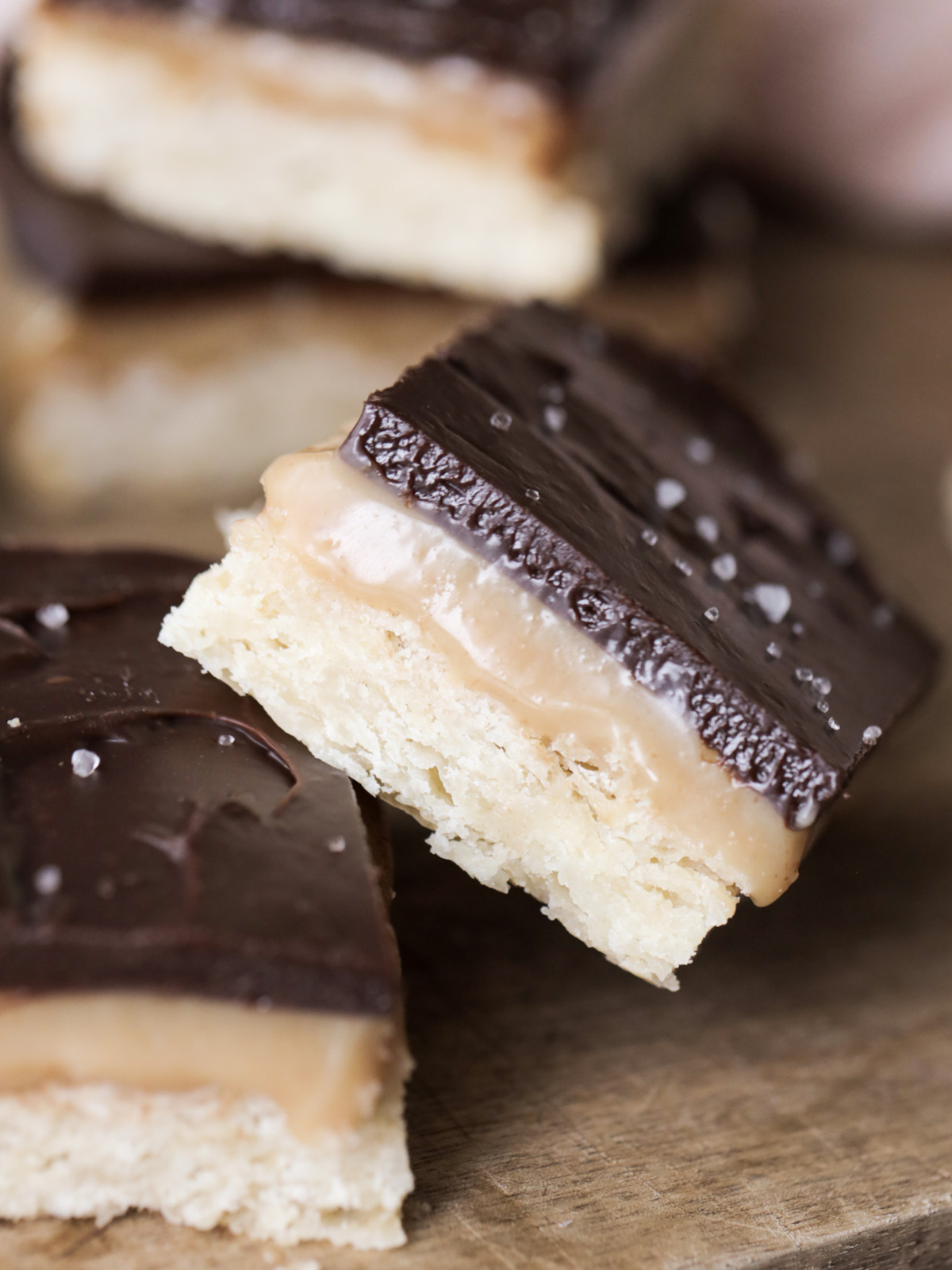 Closeup of one caramel and chocolate shortbread bar resting on another.