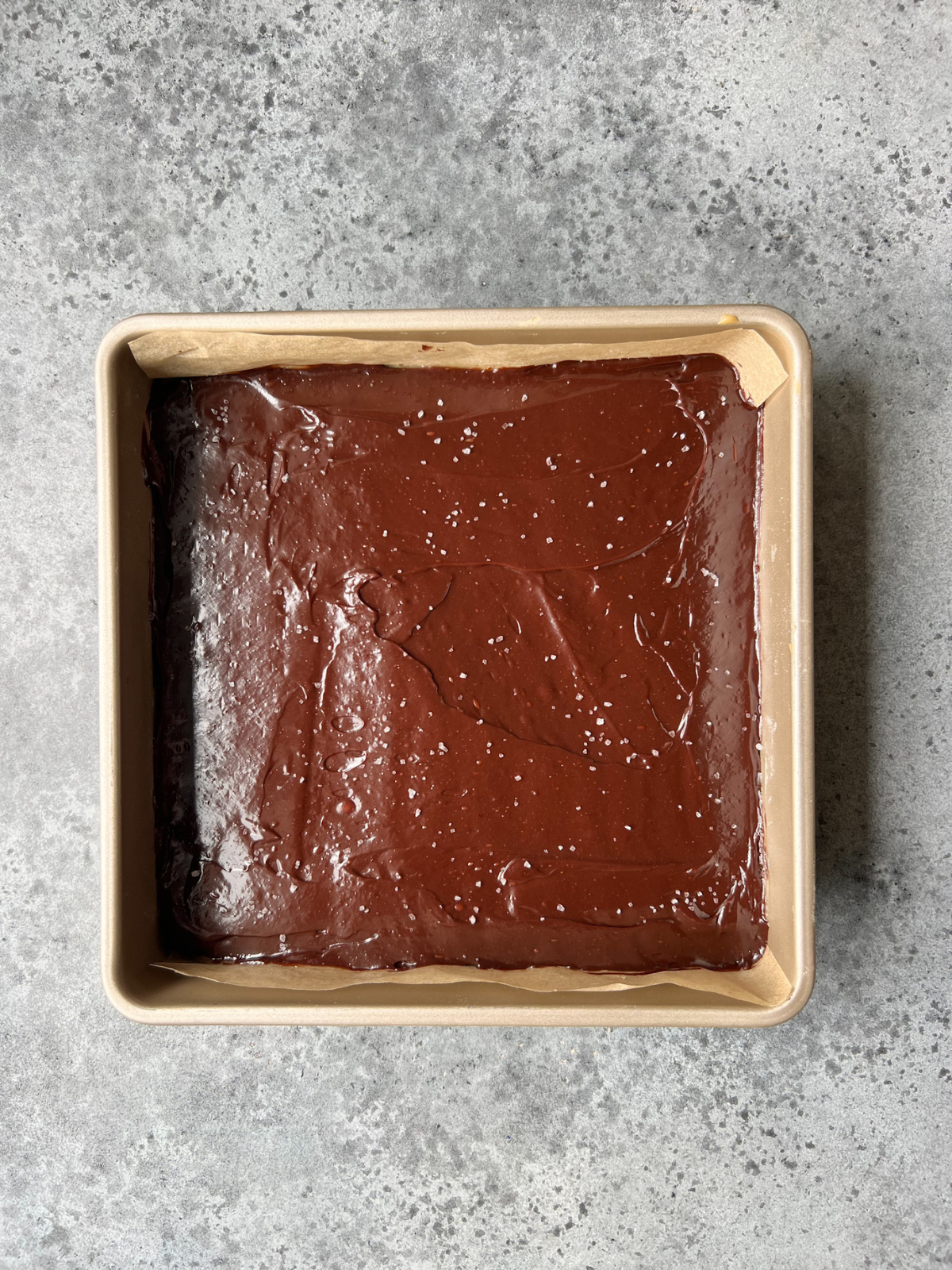 A baking pan with the chocolate ganache on top of the caramel and shortbread.