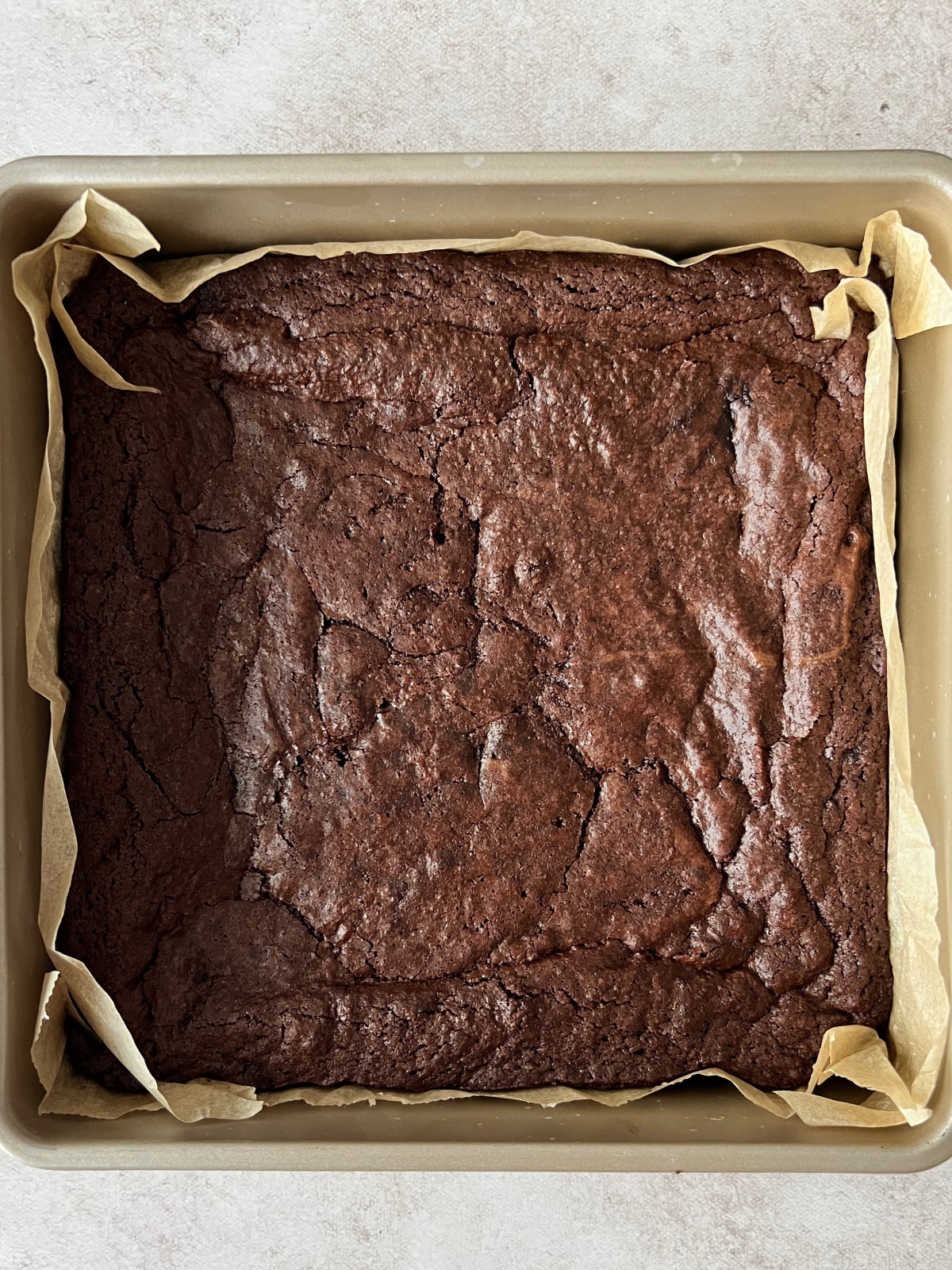 Baked brownies in a parchment paper lined 9x9 inch baking pan.