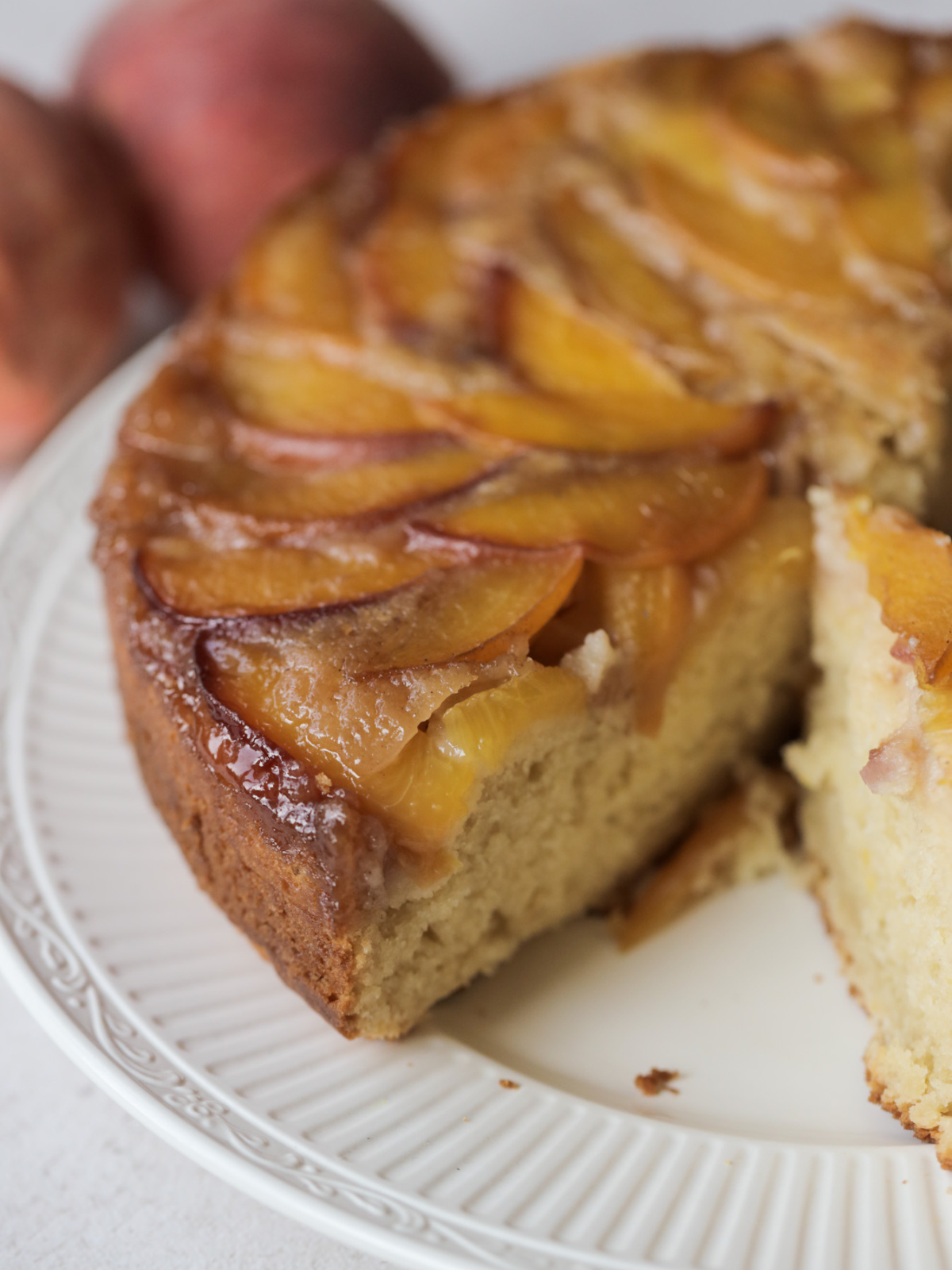 A side closeup of the peach upside down cake sits on a plate.