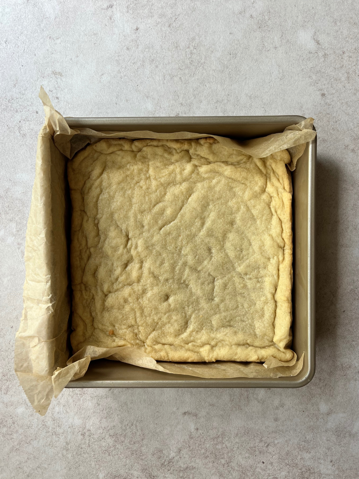 Baked sourdough sugar cookie bars fresh out of the oven sits in the baking pan.