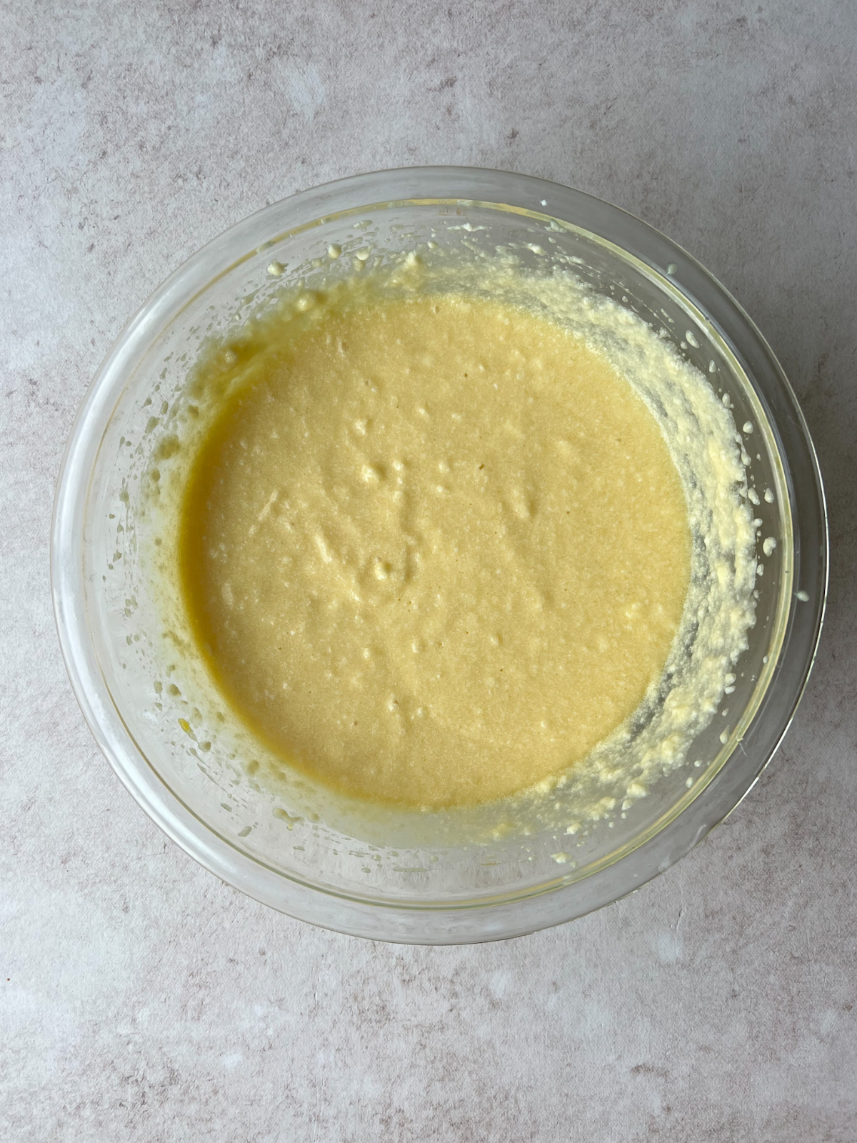 A glass mixing bowl of wet ingredients including the ricotta cheese, eggs, vanilla extract, and sugar.