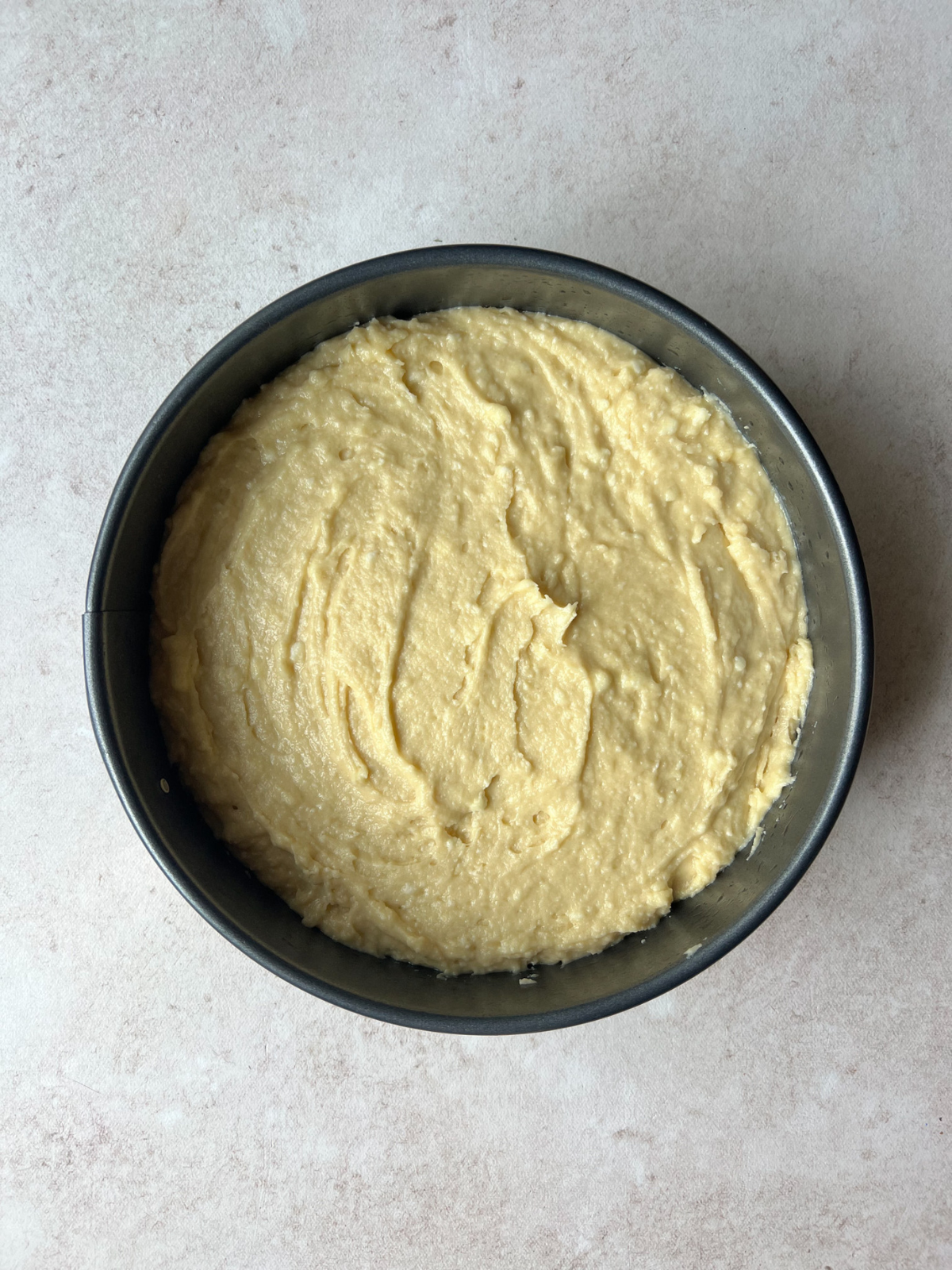 A cake pan with the cake batter over the peaches.