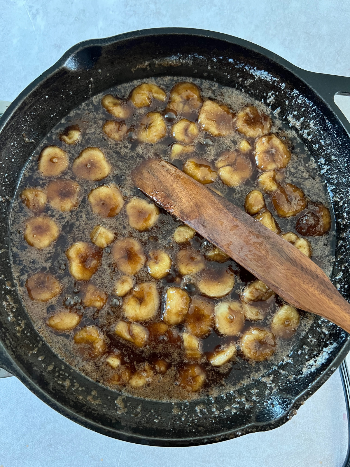 Cast iron skillet with bananas foster cooked in and sitting in it. 