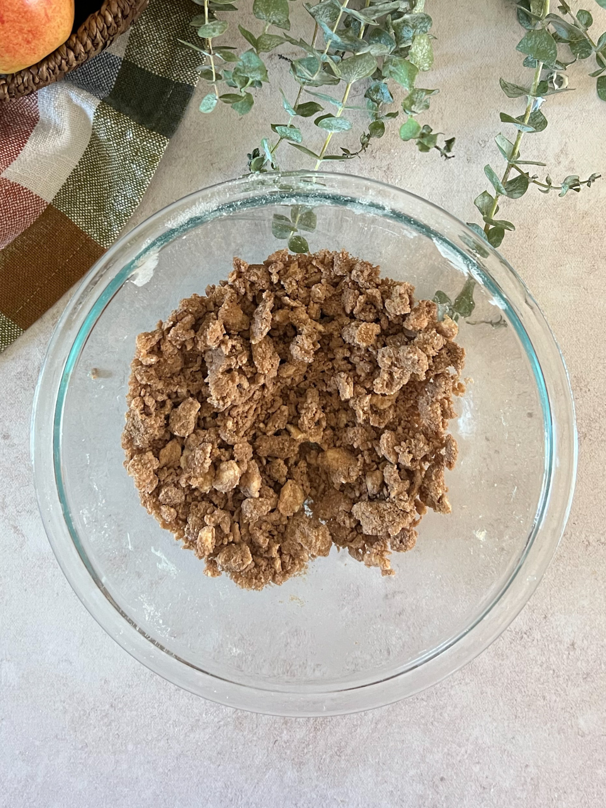 A glass mixing bowl sits with streusel crumble in it.